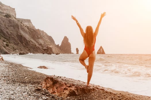 Woman sea yoga. Back view of free calm happy satisfied woman with long hair standing on top rock with yoga position against of sky by the sea. Healthy lifestyle outdoors in nature, fitness concept