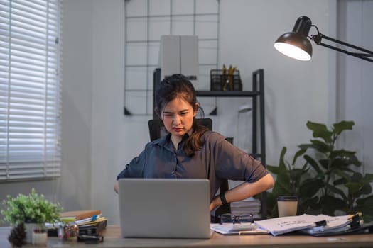 Asian businesswoman feeling tired and stressed over an unsuccessful business while working in a home office decorated with soothing green plants..