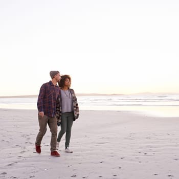 Couple, beach and walking together in nature, happy calm people on vacation. Ocean, outdoor and partners in love with respect and care, date and romantic stroll for relax with seaside sunrise.