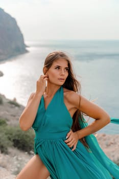 Woman sea trevel green dress. Side view a happy woman with long hair in a long mint dress posing on a beach with calm sea bokeh lights on sunny day. Girl on the nature on blue sky background