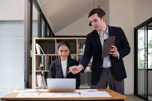 Two businessmen discussing project at the office room Businessman discusses project planning with colleagues in modern workplace while having discussion and advice on financial data report..