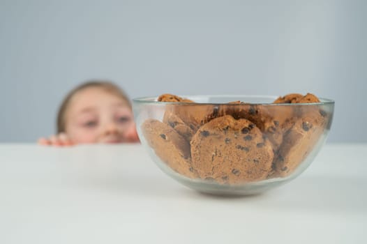 A little girl tries to steal cookies from the table