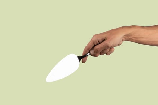 Black male hand holding a cake cutter knife isolated on green background. High quality photo