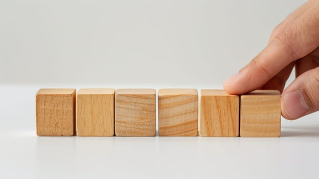 A man is holding a stack of wooden blocks. The blocks are of different sizes and are arranged in a pyramid shape. Concept of creativity and playfulness, as the man is holding the blocks in his hands