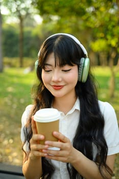 Portrait of happy woman enjoy morning coffee and listening to music in headphone outdoor.