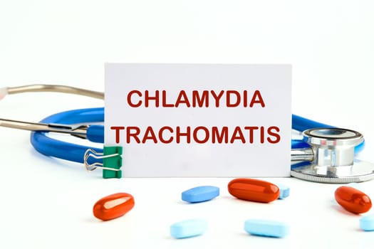 Chlamydia trachomatis on a white business card on a white background next to a stethoscope and pills, vitamins