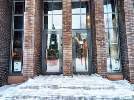 Christmas tree Through window of Snow Covered Storefront with brick columns. Background, pattern and texture