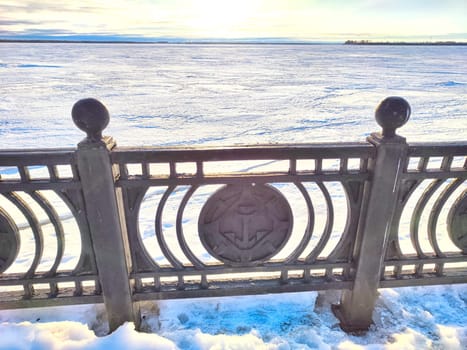 Winter Sunrise Through a Decorative forged Fence. Sunlight piercing through an ornate fence on a snowy spring or winter day