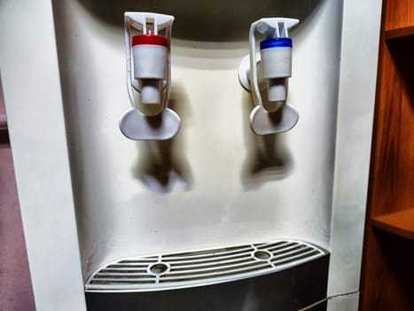 Large white water cooler with two taps. Soft serve machine with red and blue levers