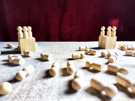 Wooden toys stand opposite and lot of lying figures. Concept of dispute between leaders of two groups. Government and deaths of citizens and soldiers. War in Russia, Ukraine, Israel, Palestine