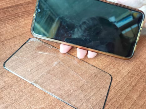 Removing Protective Film From Cracked Screen. Peeling off a cracked screen protector from a phone