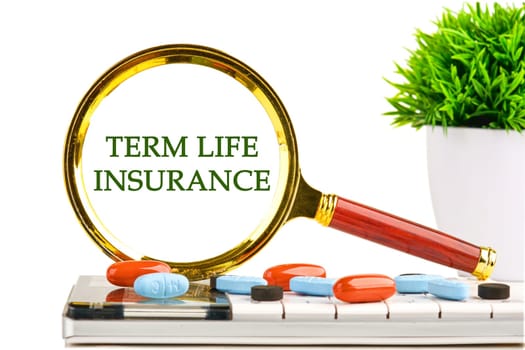 Medical concept. TERM LIFE INSURANCE through a magnifying glass on a white background on a calculator with a green plant and tablets, vitamins