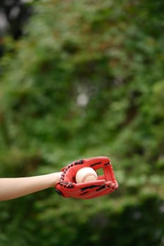 Hand in a leather baseball glove catching a ball. Sport, activity and people concept.