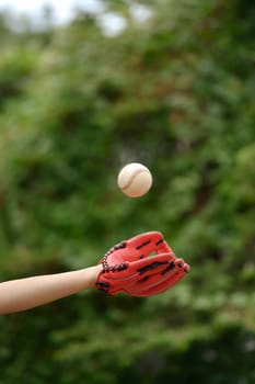 Baseball player in leather baseball glove catching a ball. Sport, activity and people concept.