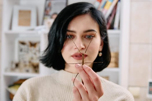 A serene moment as a young woman poses with her beloved stick insect, showcasing the unique bond between human and arachnid.