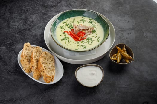Side view, seasonal cream soup with meat and vegetables on a gray stone background. Restaurant menu