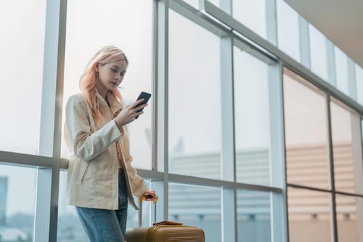 Traveler woman asian in airport and luggage for vacation, smile and holding the phone check boarding ticket. Female traveler with suitcase, international and departure with passport and trip.