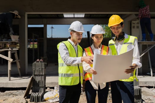 Two people are working on a blueprint, one of them is wearing a safety vest. Concept of collaboration and focus as the two individuals work together to create a detailed plan