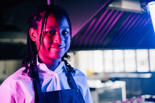 Confident female chef in uniform poses in a modern kitchen restaurant. Professional expertise successful in her occupation presenting delicious food.