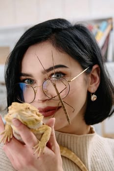 A young woman poses with her two pets, a bearded dragon and a stick insect, in this heartwarming photo.