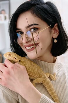 A young woman poses with her two pets, a bearded dragon and a stick insect, in this heartwarming photo.