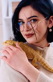 A young woman poses with her two pets, a bearded dragon and a stick insect, in this heartwarming photo.