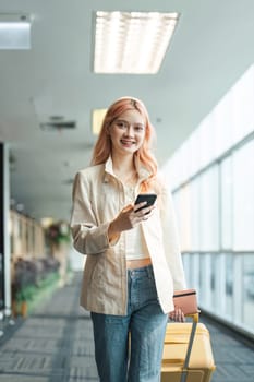 Traveler woman asian in airport and luggage for vacation, smile and holding the phone check boarding ticket. Female traveler with suitcase, international and departure with passport and trip.