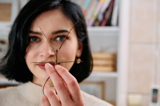 A serene moment as a young woman poses with her beloved stick insect, showcasing the unique bond between human and arachnid.