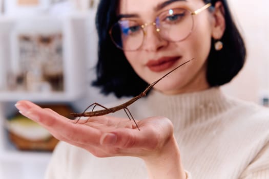 A serene moment as a young woman poses with her beloved stick insect, showcasing the unique bond between human and arachnid.