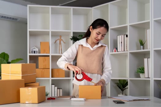 Woman asian use scotch tape to attach parcel boxes to prepare goods for the process of packaging, shipping, online sale internet marketing ecommerce concept startup business idea.