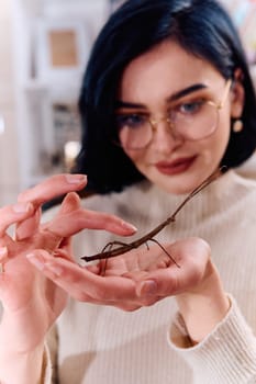 A serene moment as a young woman poses with her beloved stick insect, showcasing the unique bond between human and arachnid.