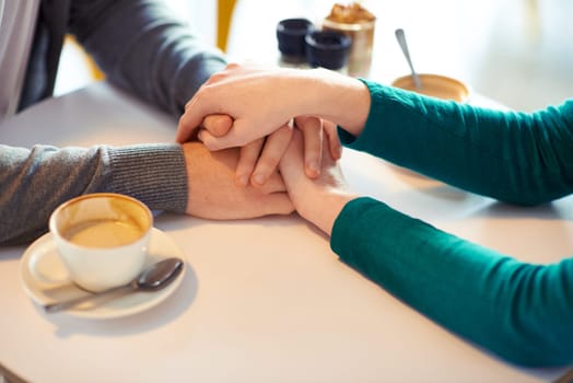 Holding hands, couple and coffee in cafe with love, romance and affection on anniversary date. Respect, together with care and bonding, loyalty and support in relationship with cappuccino for people.