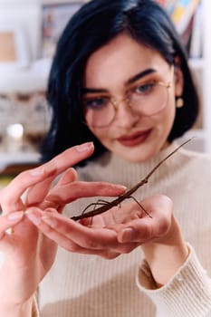 A serene moment as a young woman poses with her beloved stick insect, showcasing the unique bond between human and arachnid.