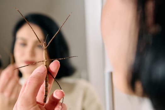 A serene moment as a young woman poses with her beloved stick insect, showcasing the unique bond between human and arachnid.