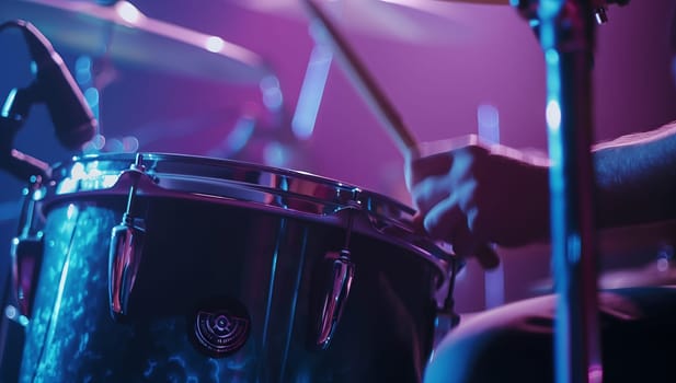 A close up of a person playing drums on stage, surrounded by vibrant hues of violet, magenta, and electric blue. The musical instrument is the focal point of this artistic entertainment event