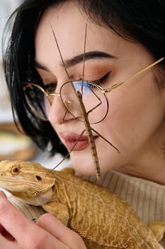 A young woman poses with her two pets, a bearded dragon and a stick insect, in this heartwarming photo.