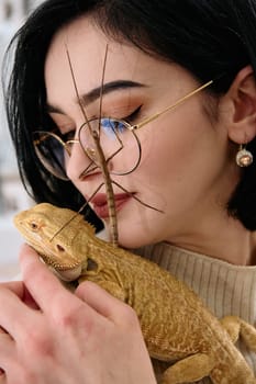 A young woman poses with her two pets, a bearded dragon and a stick insect, in this heartwarming photo.