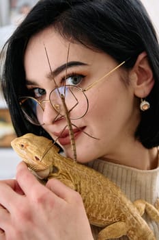 A young woman poses with her two pets, a bearded dragon and a stick insect, in this heartwarming photo.