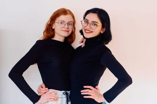 Two sisters, one brunette and one redhead, share a tender embrace, epitomizing the enduring bond of sisterhood against a backdrop of pristine white.