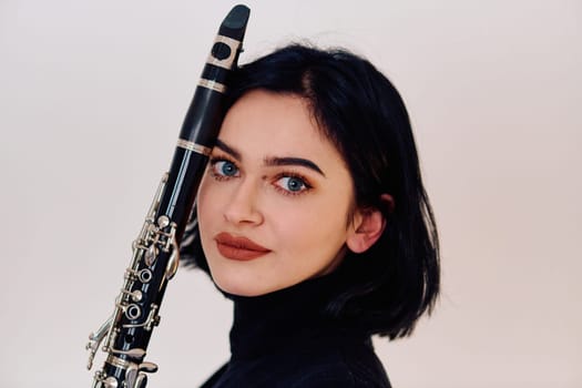 A talented brunette musician showcases her artistry as she gracefully holds and plays the clarinet against a pristine white background