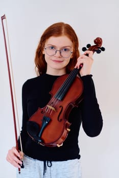 A stunning redhead musician exudes elegance as she poses with her violin, embodying both grace and musical prowess.