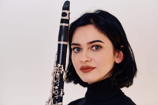 A talented brunette musician showcases her artistry as she gracefully holds and plays the clarinet against a pristine white background