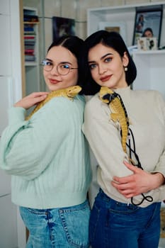 The sisters' smiles and the lizard's calm demeanor suggest that they are all enjoying each other's company.