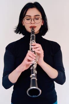 A talented brunette musician showcases her artistry as she gracefully holds and plays the clarinet against a pristine white background