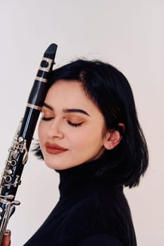 A talented brunette musician showcases her artistry as she gracefully holds and plays the clarinet against a pristine white background