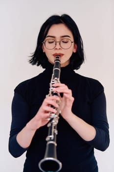 A talented brunette musician showcases her artistry as she gracefully holds and plays the clarinet against a pristine white background