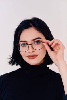 A brunette woman radiates joy as she proudly wears her eyeglasses, showcasing a warm smile against a clean white backdrop