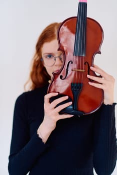 A stunning redhead musician exudes elegance as she poses with her violin, embodying both grace and musical prowess.