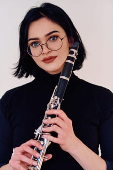 A talented brunette musician showcases her artistry as she gracefully holds and plays the clarinet against a pristine white background