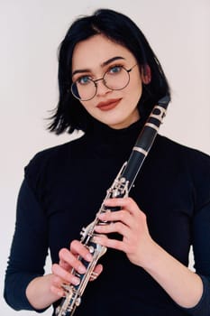 A talented brunette musician showcases her artistry as she gracefully holds and plays the clarinet against a pristine white background